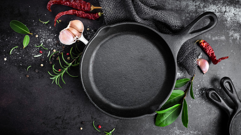 Cast iron pan on black background with spices