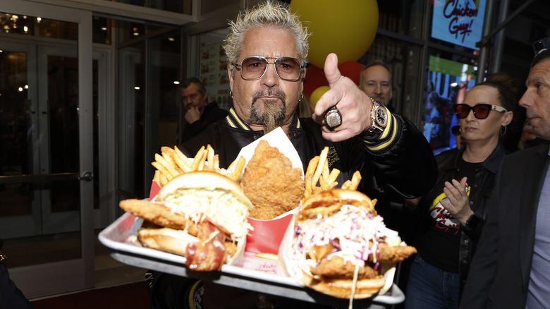 Guy Fieri holding a tray of chicken burgers and fries