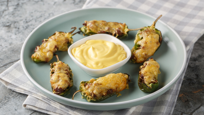 stuffed jalapeños with dip on blue plate