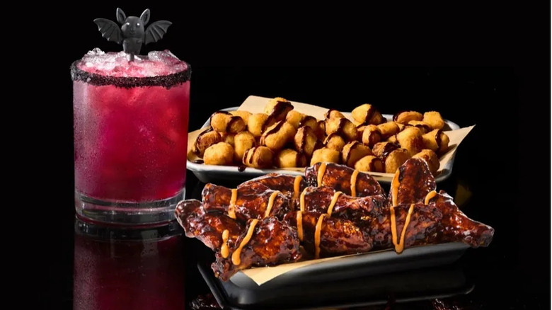 A platter of Vampire Hunter Wings from Buffalo Wild Wings sit against a black backdrop with cocktail and cheese curds
