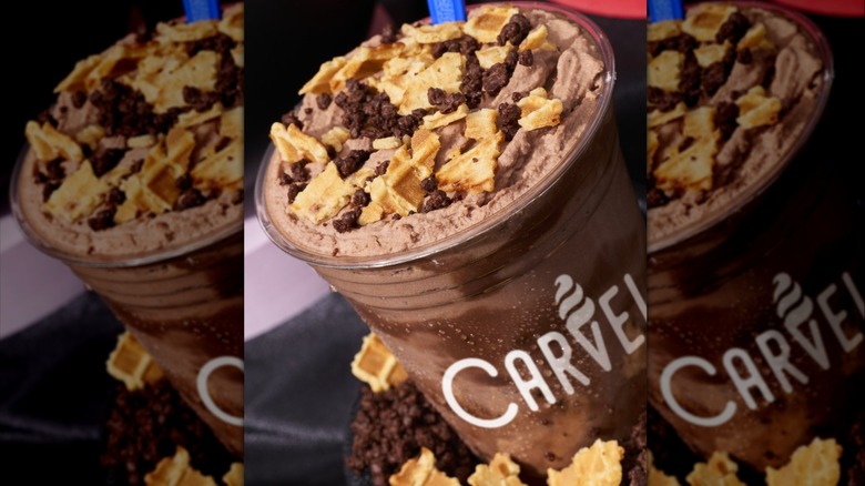 Carvel's Crunchie Munchie Monster Carvelanches photographed against a black backdrop, surrounded by chocolate crumbles and waffle cone pieces