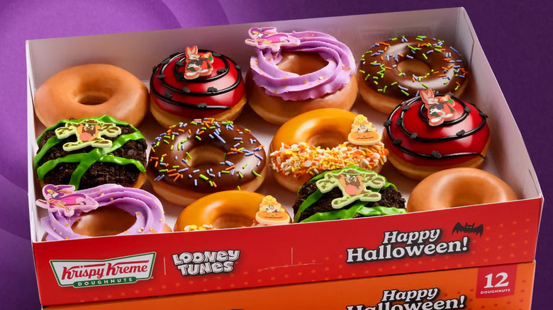 Boxes of Krispy Kreme Halloween Donuts sit stacked together against a purple background