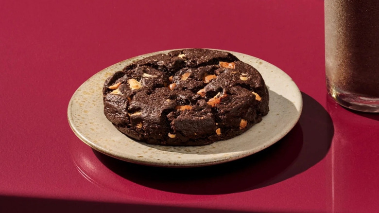 aAVenti Black Night Cookie sits on a white speckled plate settled on a purple counter