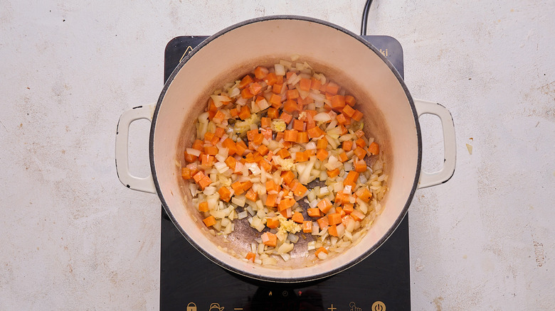 adding garlic to pot with vegetables