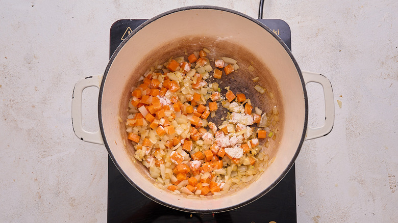 mixing flour into vegetables in pot
