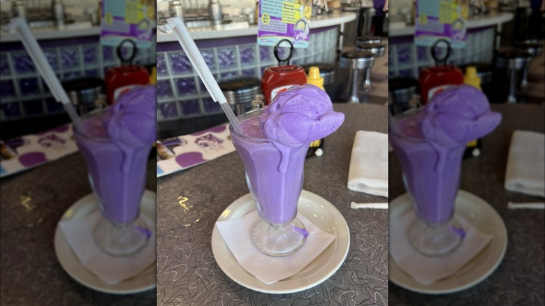 The Purple Cow milkshake topped with scoop of purple ice cream with straw sticking out of glass