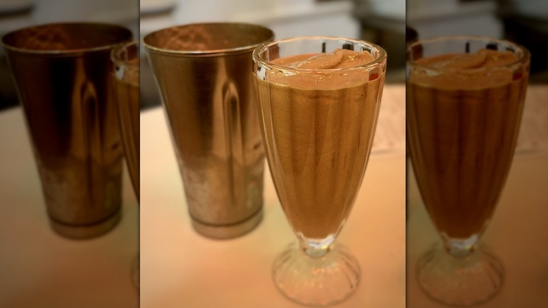 Chocolate malt in glass next to metallic container