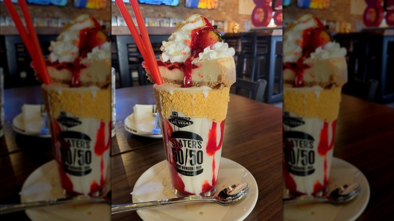 Strawberry cheesecake milkshake topped with whole slice of cheesecake and whipped cream