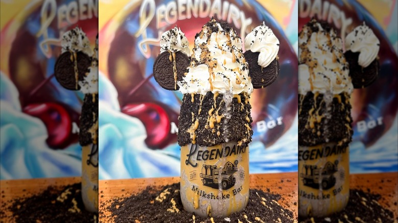 Vegan milkshake in glass decorated with crushed Oreos and whipped cream to resemble Mickey Mouse