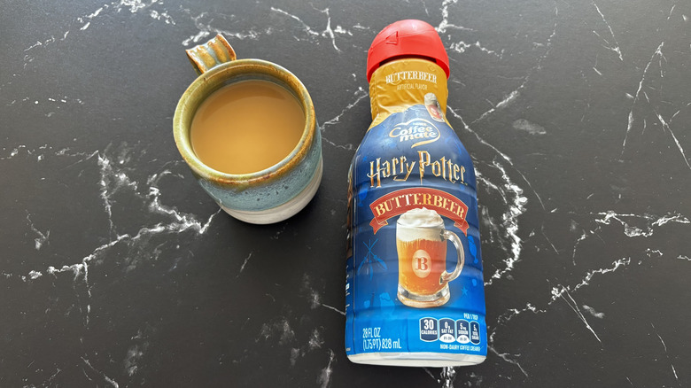 Harry Potter x Coffee mate Butterbeer Flavored Creamer bottle next to cup of coffee
