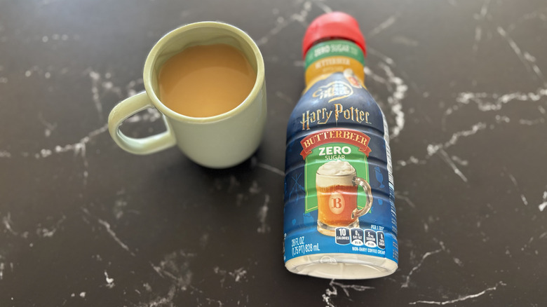 Harry Potter x Coffee mate Butterbeer Zero Sugar Flavored Creamer bottle next to cup of coffee