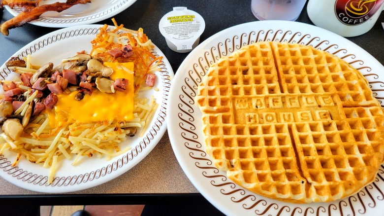 Two plates with waffle and loaded hash browns on table at Waffle House restaurant