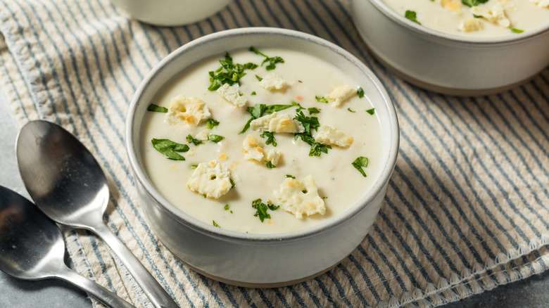 bowl of new england clam chowder garnished with parsley and broken crackers