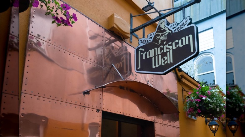 Brewpub sign in front of brass-paneled wall and hanging baskets