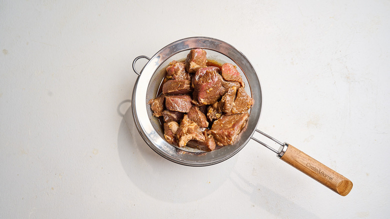 marinated beef in a colander