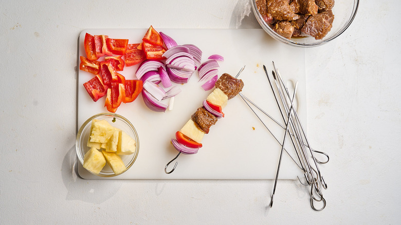 threading beef and vegetables onto skewers