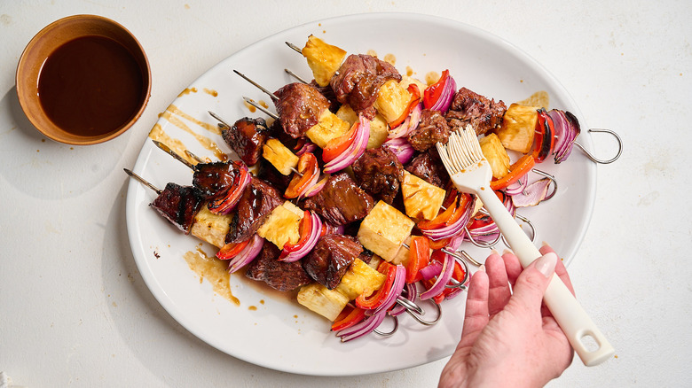brushing kabobs with teriyaki sauce