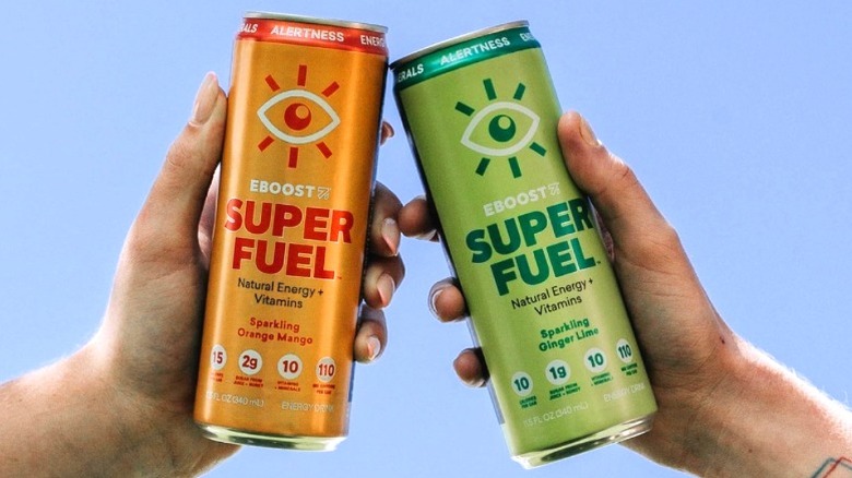Hands holding two cans of EBOOST energy drinks with the sky in the background