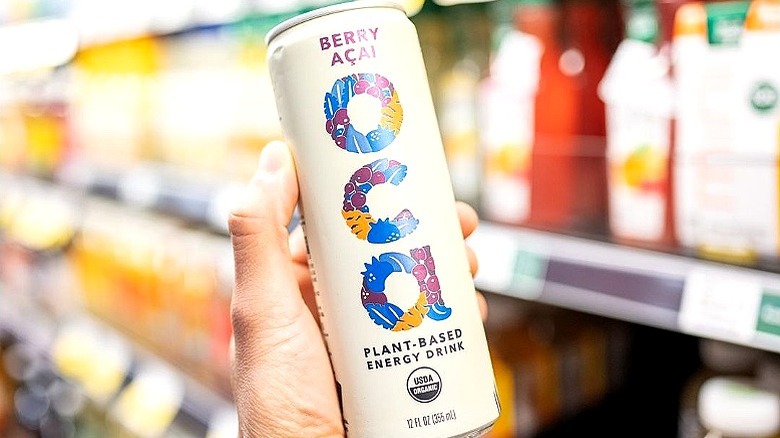 hand holding OCA drink in front of store shelves