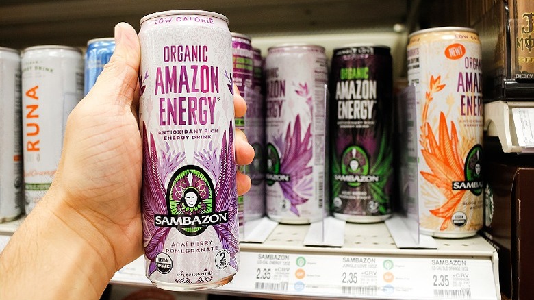 hand holding sambazon drink in front of shelf full of energy drinks at store