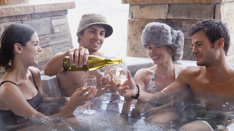 Friends drinking white wine in hot tub