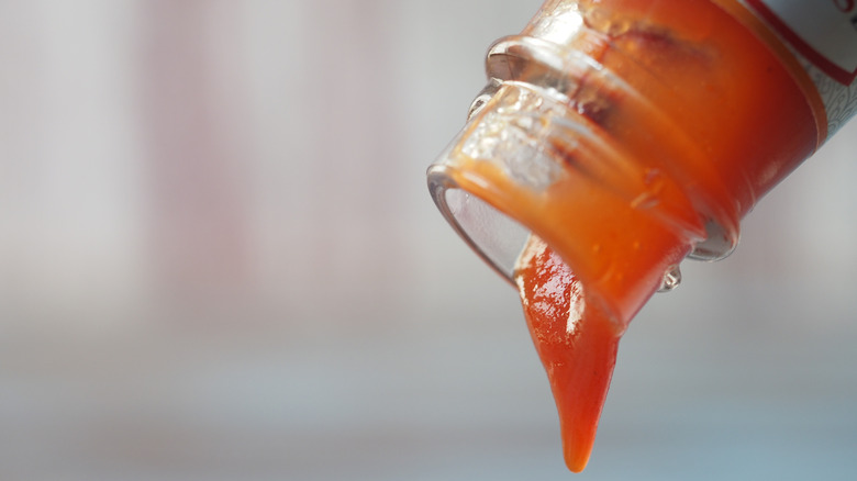 Ketchup pouring out of the mouth of a glass bottle
