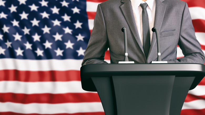 body of politician wearing suit in front of USA flag