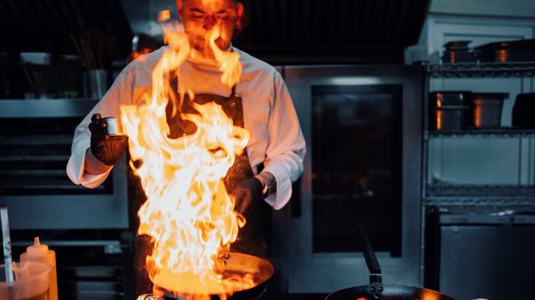 A man cooking in a kitchen with big flame