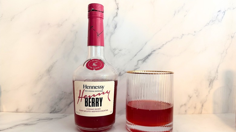Bottle of Hennessy Henny Berry Very Special Cocktail next to cocktail in glass on marble surface