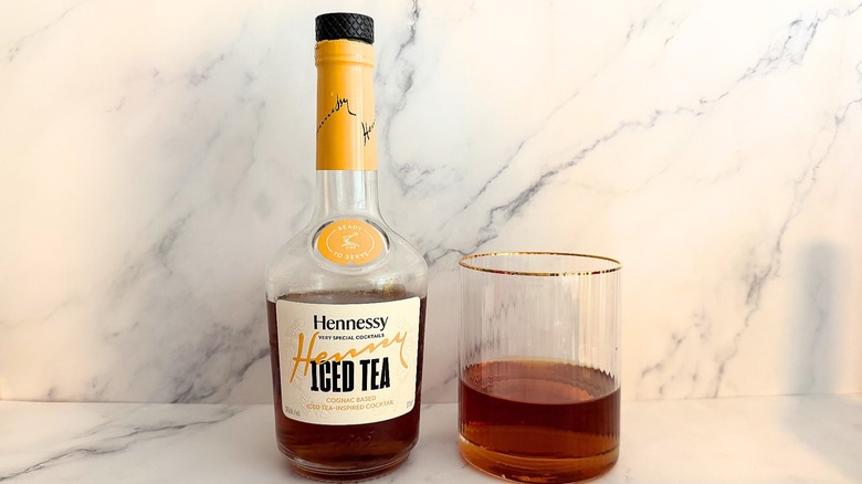 Bottle of Hennessy Henny Iced Tea Very Special Cocktail next to cocktail in glass on marble surface