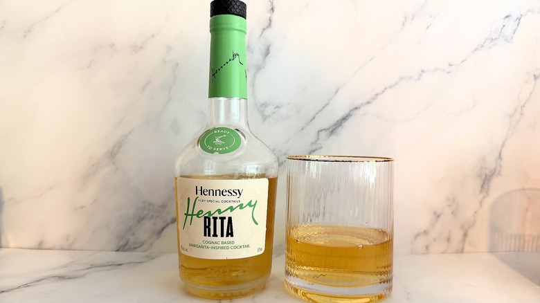 Bottle of Hennessy Henny Rita Very Special Cocktail next to cocktail in glass on marble surface