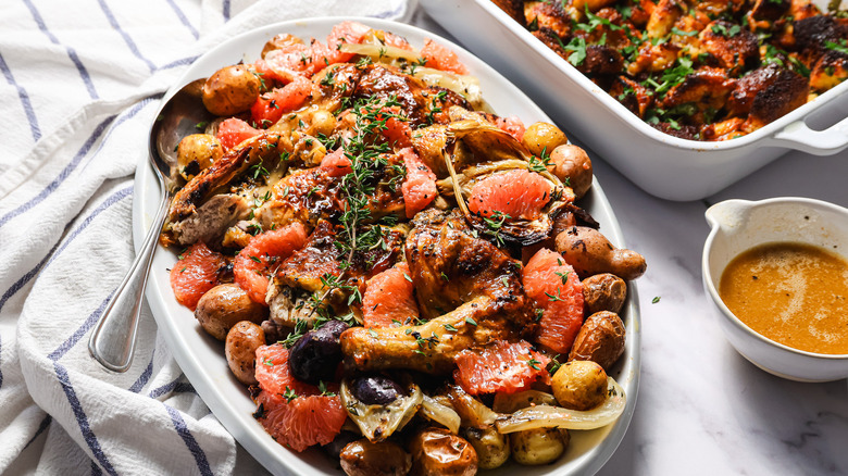 Herb roasted spatchcock chicken on a platter beside brioche stuffing pan and au jus