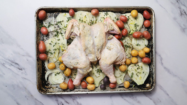 Seasoned chicken and veggies in baking sheet