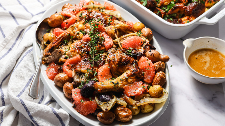 Herb roasted spatchcock chicken on a platter beside brioche stuffing pan and au jus