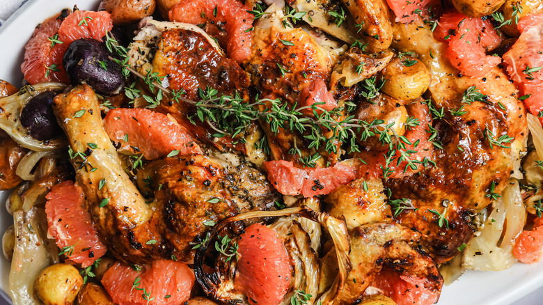 Herb roasted spatchcock chicken in a plate with potatoes, fennel, grapefruit and thyme