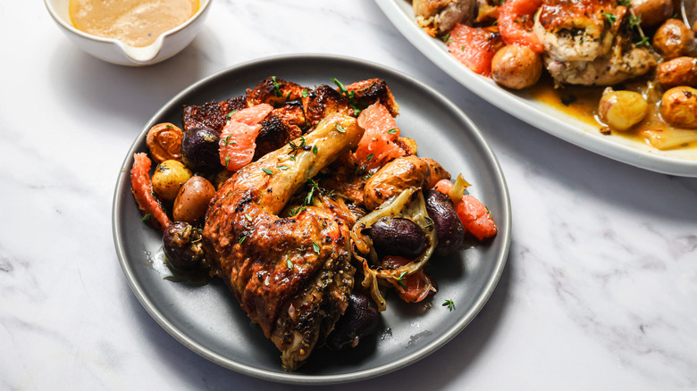 Herb roasted spatchcock chicken on a plate beside platter with more chicken