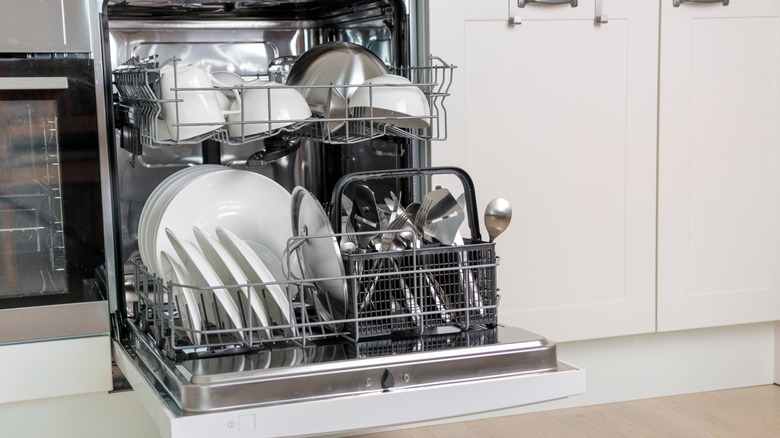 Open dishwasher full of clean dishes, with top and bottom rack pulled out