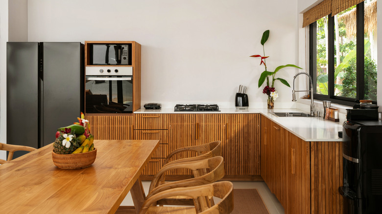 A bright kitchen with wooden cabinets and a dining table in a modern luxury villa