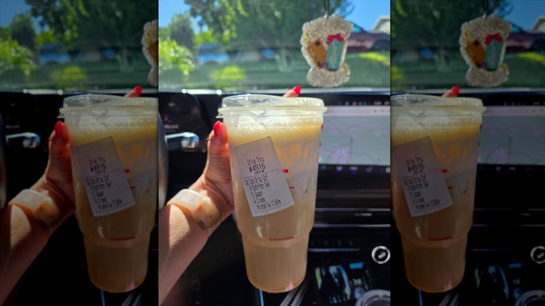 Hand holding Dunkin' Peanut Butter Dunkalatte in car