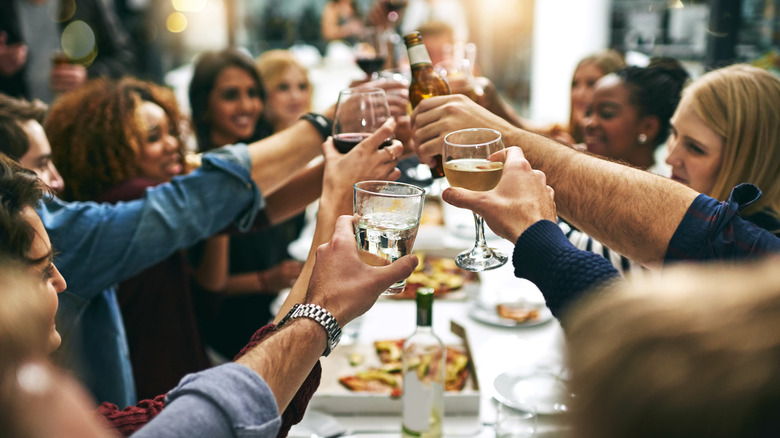 Cropped shot of a group of young friends toasting during a dinner party at a restaurant