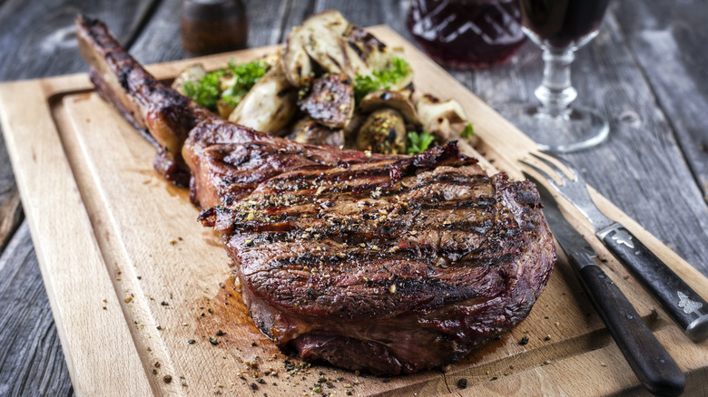 grilled tomahawk steak on cutting board with Brussels sprouts