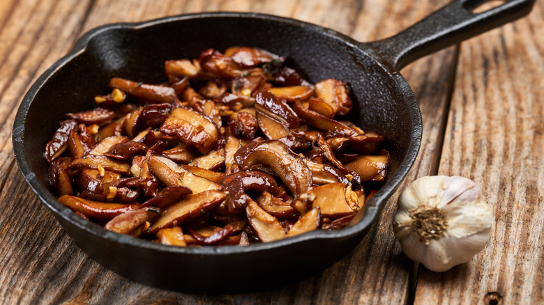 cooked mushrooms in a skillet next to garlic