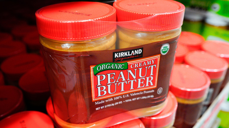 A two-pack of Kirkland Signature organic creamy peanut butter on a store shelf.
