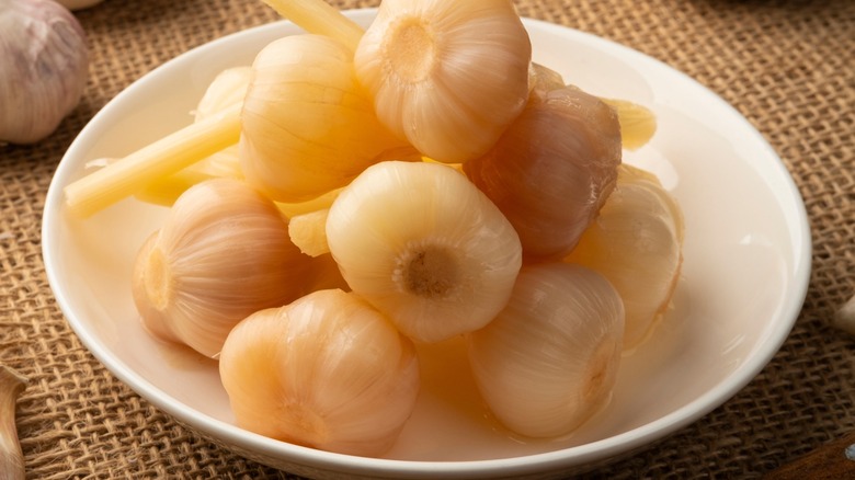 Closeup of a bowl of pickled garlic heads