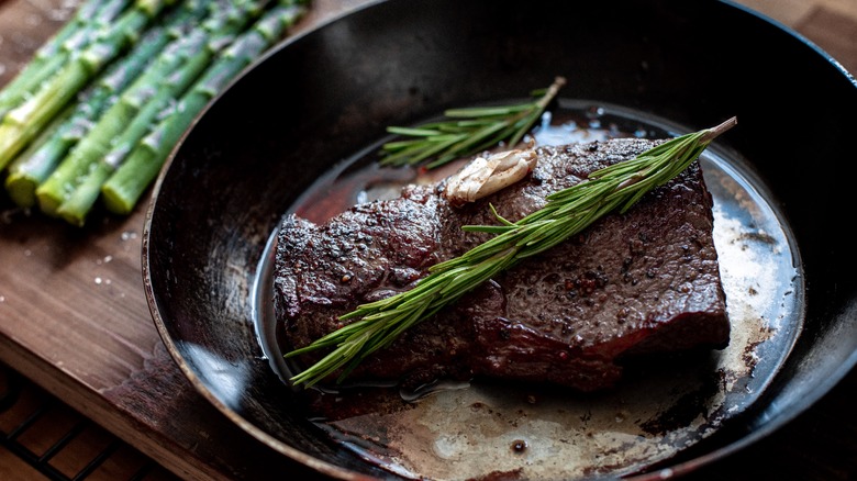 Steak with rosemary in a carbon steel pan
