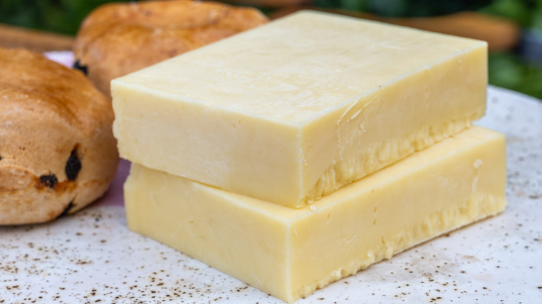 Two blocks of white cheddar cheese, stacked.