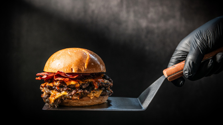 Hand holding scraper with smash burger