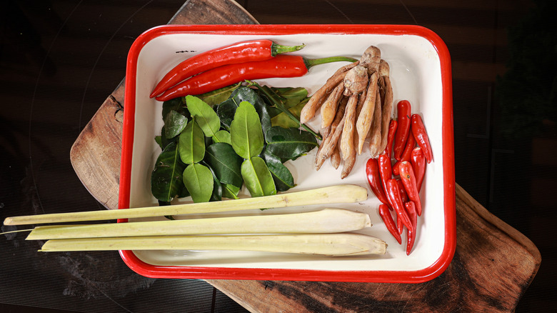 a red and white dish filled with chilies, lemongrass, galangal, and kaffir lime leaves