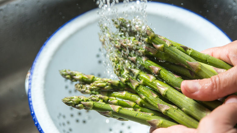Hands rinsing asparagus in sink