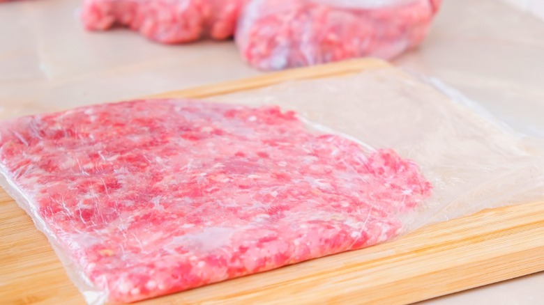 Frozen flat beef mince in a freezer bag on a wooden board